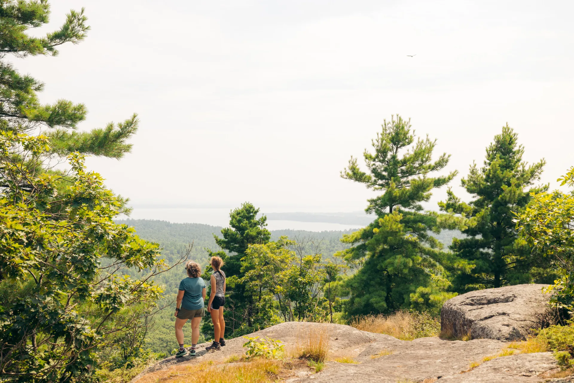 two women look out from the top of a mountain. 